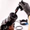 A girl photographer in gloves cleans the lens with special tools for cleaning professional optics.