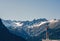 A girl photographer in a red cap with a camera stands on the balcony opposite snow Swiss Alps and forest of national park in Switz