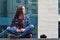 A girl photographer uses a smartphone and sits on a granite para