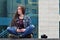 A girl photographer uses a smartphone and sits on a granite para