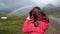 A girl photographs a beautiful rainbow with a phone