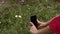 The girl photographs on a mobile phone chamomile flowers in the summer in the field. Summer mood.