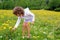 Girl picking flowers in yellow spring meadow