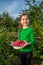 Girl picks raspberry in fruit garden into bowl