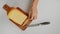 Girl picks up pieces of chopped cheese on wooden board top view. Close-up shot of woman\'s hands take cheese. Fresh