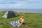 A girl on a picnic near a tent in nature by the sea on the cliff of Paldiski in the summer