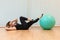 Girl pilates trainer does criss cross fitball posture in fitness center