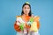 Girl with piles of garbage, surrounded by litter, looks concerned, sorts waste and recycles, blue background