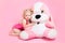 Girl in a pink bathing suit hugging a stuffed toy