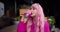 A girl in pink clothes and with pink hair drinks soda from a pink can on the street. Pink color harmony, bright