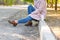 A girl in a pink coat sits on a curb in a park with coffee. Concept - rest.