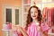 A girl in a pink dress and long curled hair with cakes at a party. Having fun, holding cakes in his hands, wants to take a bite