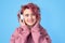 Girl with pink hair in hoodie and headphones enjoying favourite music