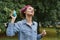 A girl with pink hair listens to music through the portable musical speaker and dances in the park in summer