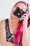 Girl with pink hair photographs camera pinup style