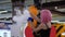 Girl with pink hair speaks into the microphone and holds boiling glass flask with smoke and blue liquid at mall