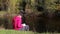 Girl in pink hoodie makes notes in a notebook sitting by the river. With sound