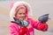 Girl in a pink jacket is feeding bread to pigeons hands