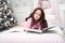 A girl in a pink knit cardigan in bed with a book