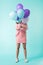 Girl in pink outfit holding balloons in front of face