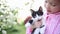 Girl in pink shirt in garden in summer. child holds kitten in his arms outdoors.