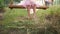 A girl in a pink skirt tutti skates on a rural homemade swing. Close-up of bare feet, grass and earth. Happy Holidays