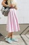 Girl in pink skirt, yellow shirt and with a backpack standing ag