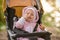 A girl in a pink suit sits in a yellow stroller and smiles, showing recently erupted teeth