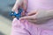 Girl in pink t-shirt is playing blue metal spinner in hands on the street, woman playing with a popular fidget spinner toy, anxiet