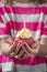 A girl in a pink and white shirt holding a pink cupcake in two hands with candle just blown out, vertical