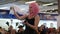 Girl in pink wig holds boiling glass flask with smoke and blue liquid at shopping center