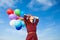 Girl in plaid dress with multicolored balloons