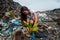 Girl planting tree among trash at garbage dump