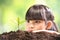 A girl planting young plant on soil with a hope of good environment