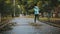 Girl play and jump in puddle in park after autumn rain. Fall rainy weather outdoors activity for young child. Kid