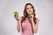Girl playfully holding green apple .