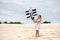 Girl playing on beach flying ship kite. Child enjoying summer.