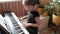 Girl playing classic digital piano during family home concert, emotional playing, side view