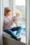 Girl playing with a doll on a windowsill