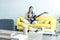 girl playing electric guitar on sofa boks and disposable cup of coffee on table