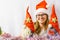 The girl is playing with homemade Christmas gnomes. A girl of 30-35 years old wearing a Santa Claus hat. Handmade Scandinavian