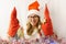 The girl is playing with homemade Christmas gnomes. A girl of 30-35 years old wearing a Santa Claus hat. Handmade Scandinavian