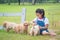 Girl playing with little golden retriever dog in par