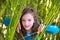 Girl playing in nature peeping from green canes