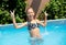 girl playing in outdoor swimming pool jumping into water on summer vacation. Child learning to swim in outdoor pool