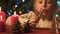 Girl playing with pine cones and wooden Christmas toys, festive atmosphere