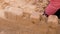 Girl playing with sand on the yard. Construction of sand castle