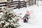 Girl playing with a snowman with pink knitted scarf