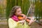 Girl playing the violin in the autumn park at a lake and willow foliage background