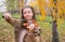 Girl playing the violin in the autumn park at a yellow foliage b